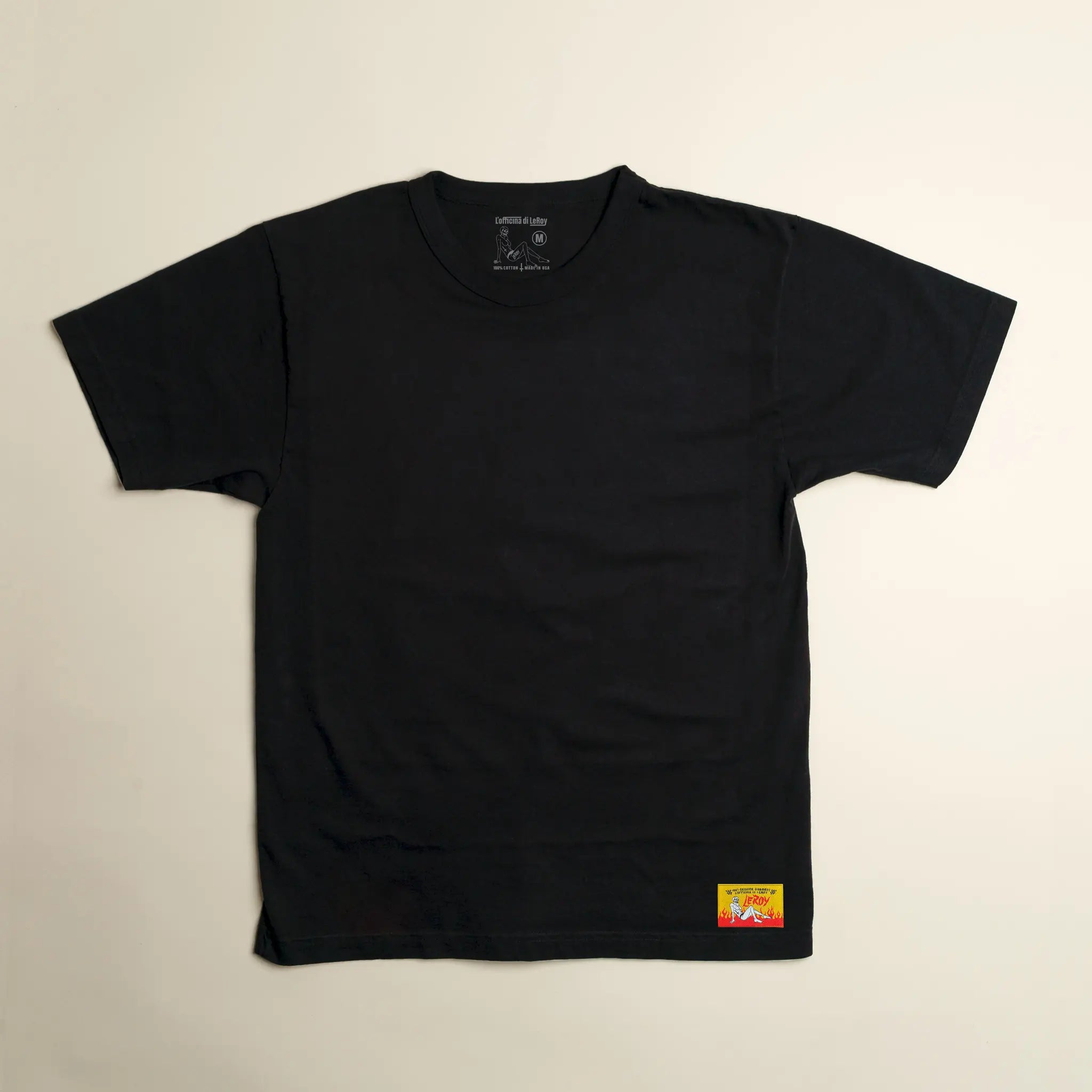 A black LeRoy Label Heavy Weight T-Shirt laid flat on a light background, featuring a small woven label with red lettering on the bottom right.