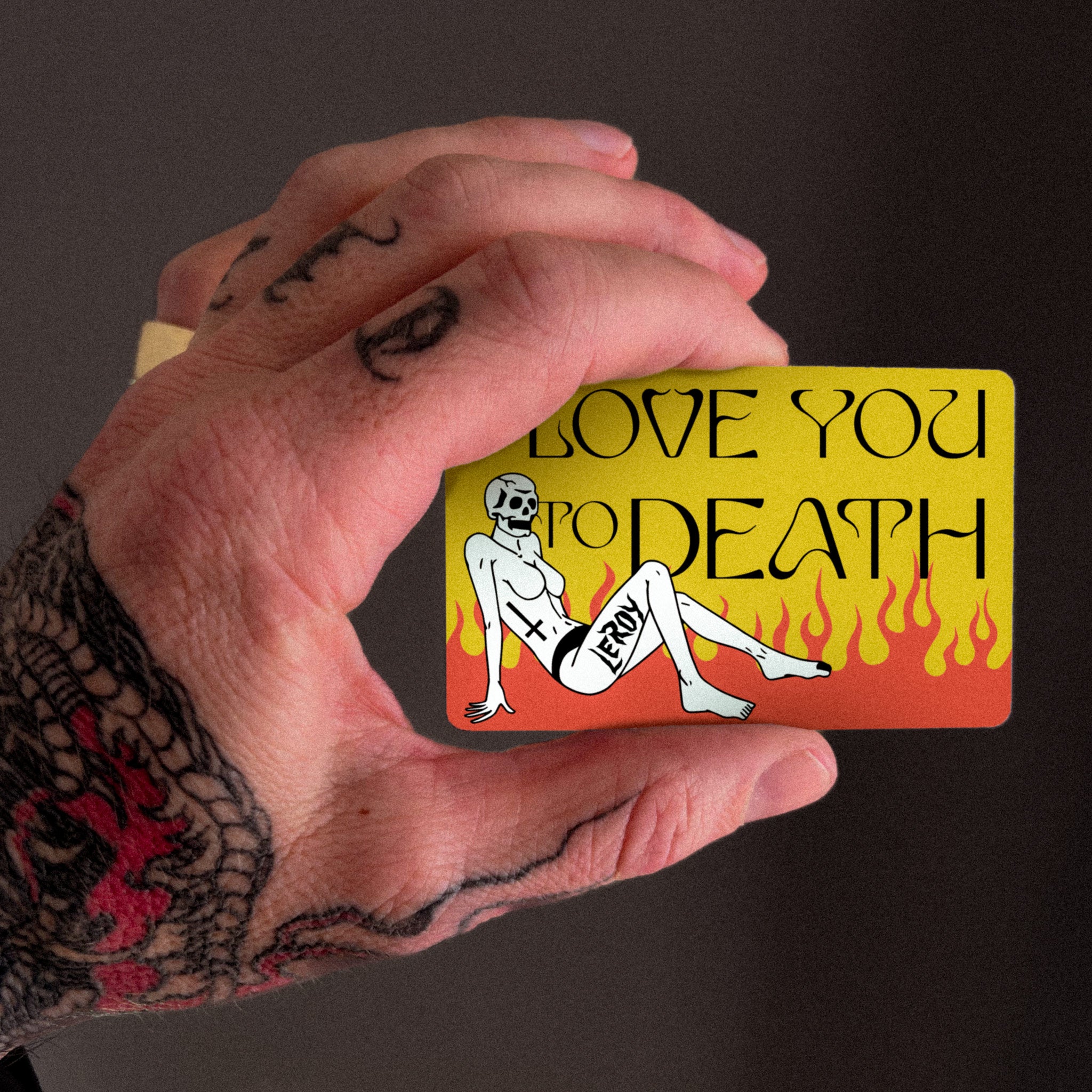 tattooed hand holding gift card that reads, "LOVE YOU TO DEATH"